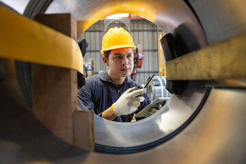 Engineer worker inspecting industrial metal rolls with tablet
