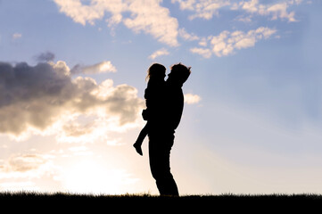 Silhouette of Happy Father Lovingly Hugging Little Child Outside