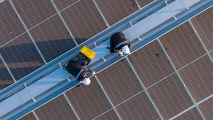 Aerial view of engineers inspecting rooftop solar panels