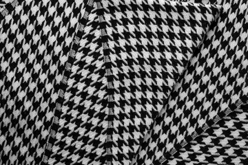 Close-up of black and white houndstooth scarf with visible folds and texture.