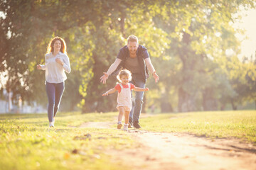 Naklejka premium Young happy parents with their baby girl having fun outdoors