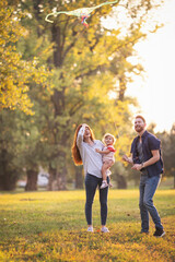 Fototapeta premium Young happy parents with their baby girl having fun outdoors