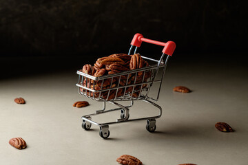 Pecan nuts in a miniature shopping cart evoke playful indulgence in food