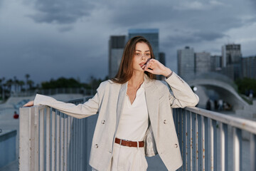 Fototapeta premium Confident woman in a light business suit on a city backdrop exuding professionalism and poise, showcasing modern business style and elegance.
