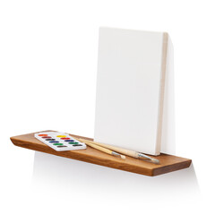 Blank canvas, brushes and paints on oak wooden shelf isolated on white background, angle view,...