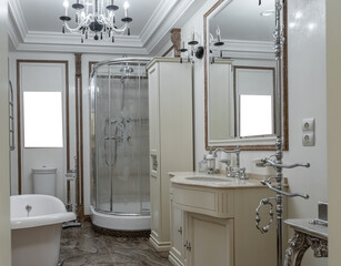 elegant bathroom in retro style. chrome faucet, large sink, mirror in frame. large white bathtub, large shower cabin. brown, white and beige ceramic tiles on walls. Bathroom design in luxury housing. 