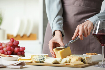 Woman slicing delicious cheese at light textured table indoors, closeup