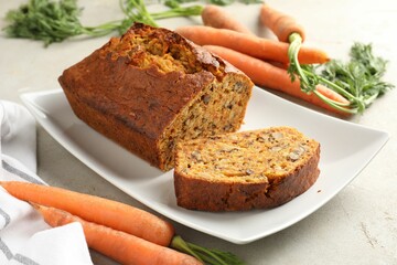 Homemade carrot cake with nuts and vegetables on light grey table, closeup