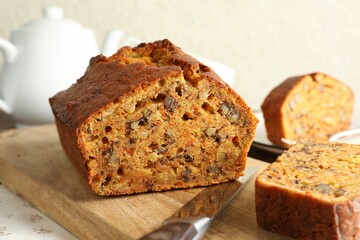Cut homemade carrot cake with nuts and knife on table, closeup