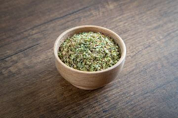 A bowl full of dried and ground organic mountain thyme on wooden table
