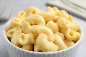 Delicious pasta with cheese sauce in bowl on table, closeup