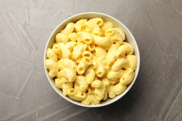 Delicious pasta with cheese sauce in bowl on grey table, top view