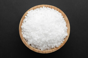 Salt in bowl on black background, top view