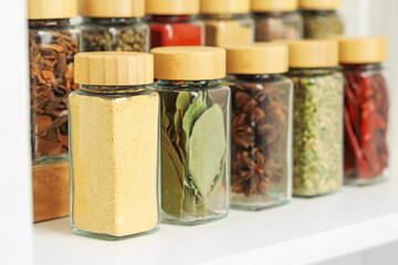 Many different aromatic spices in jars on white table indoors, closeup