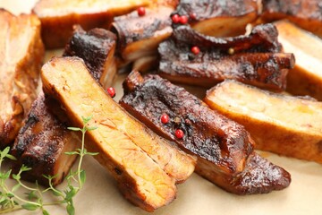 Delicious pork ribs and thyme on parchment paper, closeup