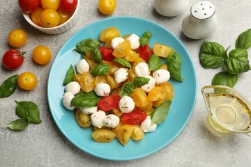 Tasty salad with yellow tomatoes, basil and mozzarella cheese on light grey table, flat lay