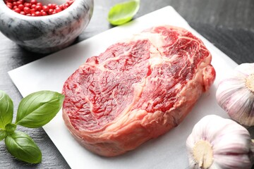 Piece of raw beef meat and spices on black table, closeup