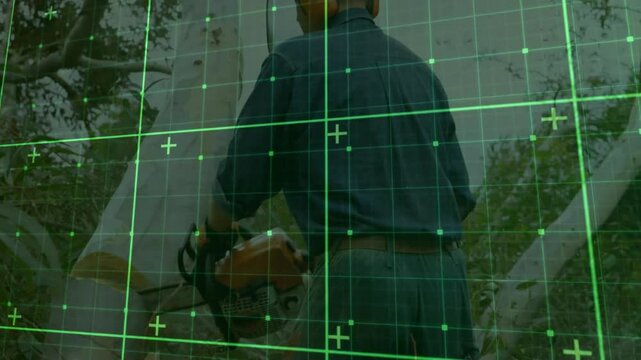 Man wearing gloves operating orange chainsaw on tree trunk under technology grid overlay