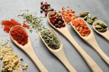 Many different spices in spoons on grey table, closeup