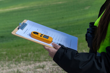 Measuring wind speed for renewable energy development with anemometer and clipboard