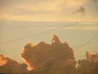 Vibrant sunset clouds illuminated by golden sunlight with electric wires silhouetted across the sky