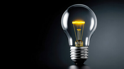 Bright light bulb glowing with yellow filament on dark background showcasing illumination concept