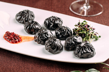 Portion of gourmet black colored dumplings with sauce