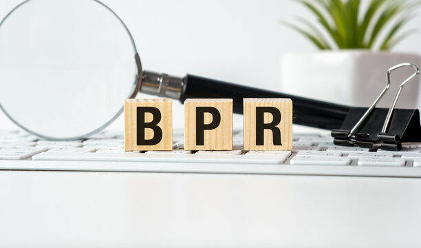A magnifying glass is on a table with a keyboard and a stack of blocks