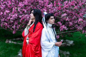 A male cosplayer with long hair in a kimono against a sakura background