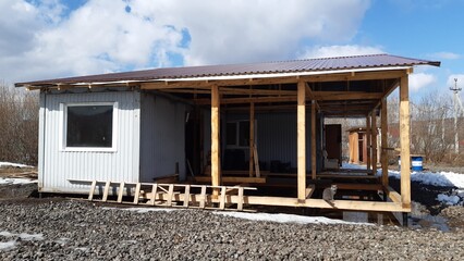 Fototapeta premium Construction of a modern wooden cabin in a rural area during early spring