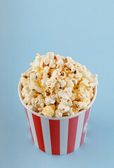 Classic red striped popcorn cardboard cup on blue background