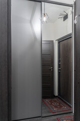 stylish corridor design in flat, apartment, hotel room or house. gray walls. wooden doors, beautiful chandeliers on ceiling. Soft lighting. furniture and entrance hall. large mirror in hallway