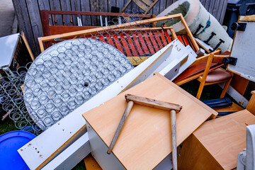 Discarded furniture and debris cluttering a vacant lot in an urban area during daylight hours