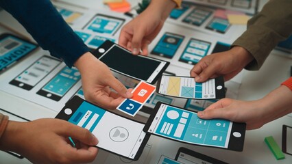 Hands are actively engaging with smartphone mockups and wireframes during a collaborative design session in an office environment, showcasing teamwork and creativity. SACTR