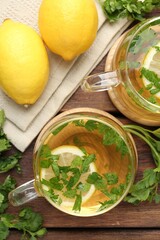 Healthy parsley tea with lemon slices on wooden table, flat lay. Detox drink