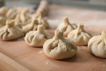 Many uncooked khinkali on table indoors, closeup