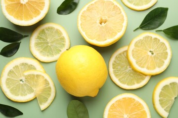 Fresh lemons and leaves on pale green background, flat lay