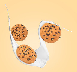 Tasty chocolate chip cookies and milk splash on beige background