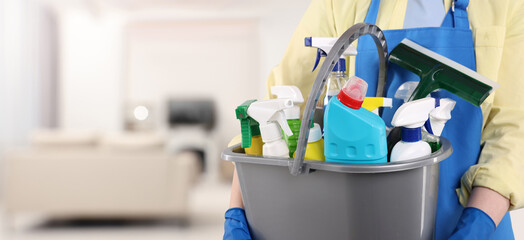 Woman with different cleaning supplies and products in room, closeup. Banner design and space for text