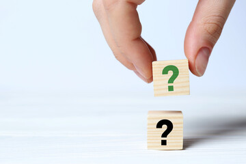 Woman holding cube with question mark at white table, closeup. Space for text