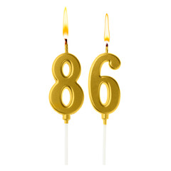 Burning golden cake candles composing number 86 on white background. Festive decoration for...