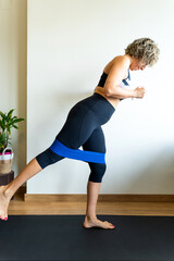 Woman performing leg exercise with resistance band at home