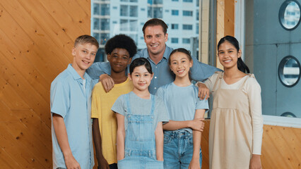 Happy teacher and diverse student standing while smilling to camera. Professional smart instructor with highschool children with mixed races in casual outfit pose at camera with cheerful. Edification.