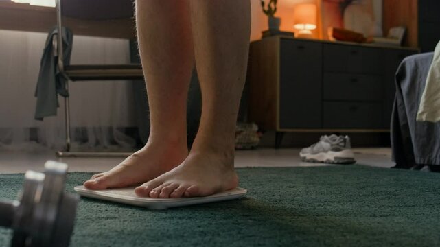 Unrecognizable barefoot man steeping on digital white scale to check body mass