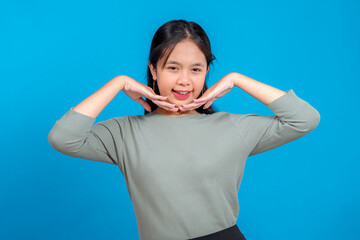 Cheerful young Asian woman smiling with hands under chin in a cute pose, expressing joy and...