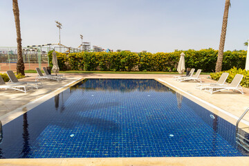 Summer seaside relax mood travel vacation a luxurious pool hotel interior for a summer holiday in warm countries. Beautiful tropical beach hotel resort with swimming pool, sun loungers palm trees