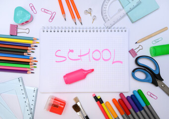 Top view of notebook with SCHOOL lettering surrounded by vibrant school tools. Perfect for back-to-school promotions and kids education design. Great for educational blogs or creative ads.
