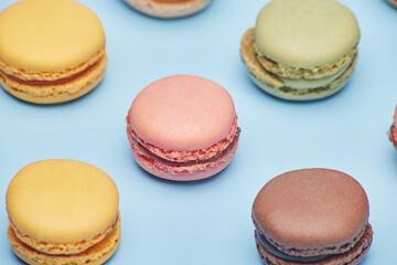 Fresh small various color macaron biscuit cookies pattern isolated on the bright solid fond plain bright blue background