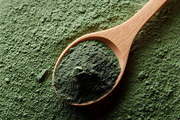 1Heap green spirulina algae powder in wooden spoon.