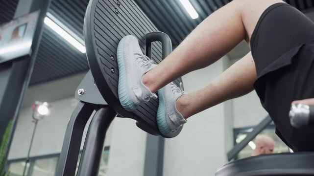 Leg view of gym enthusiast pushing leg extension machine, showing tense calf muscles engaged in controlled extension under modern gym lighting emphasize strength endurance and focused technique